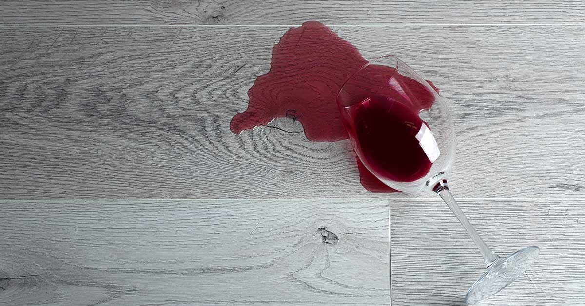 Una copa de vino tinto derramada sobre el piso vinilico LVT. Aparentemente debería limpiarse fácilmente sin dejar manchas